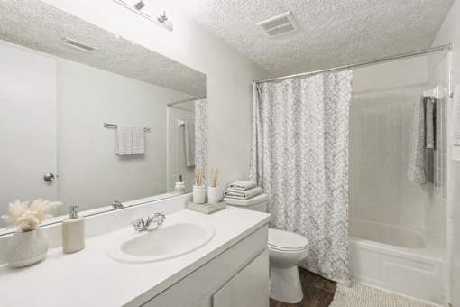 A white bathroom with a sink, toilet, and shower at Emerald Pointe, Riverdale, GA