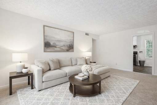 A living room with a white couch, a coffee table, and a painting on the wall at Emerald Pointe, Riverdale, GA