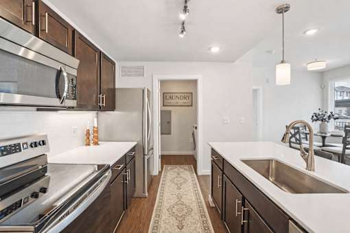 Modern kitchen with laundry room access at Connect at First Creek Apartments, Denver, CO 80249