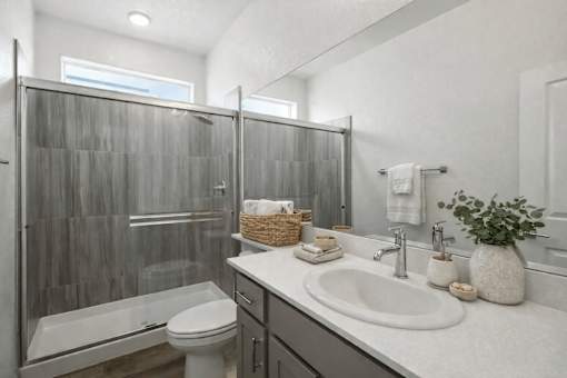 A bathroom with a white toilet, a white sink, and a glass shower stall.