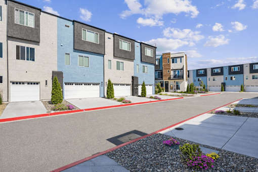 A row of modern townhouses with garages and landscaped front yards.