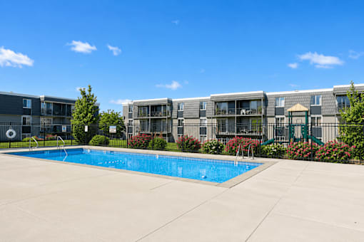 Swimming pool with surrounding deck and playground at Park Station Apartments, Midvale, 84047