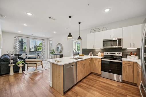 Open kitchen with white countertops and wood cabinets at Sequel Homes Apartments, Englewood
