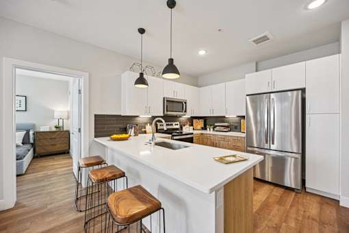 Modern kitchen with white island and pendant lights at Sequel Homes Apartments, Colorado, 80110