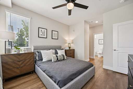 Bedroom with gray upholstered bed and ceiling fan at Sequel Homes Apartments, Englewood, Colorado
