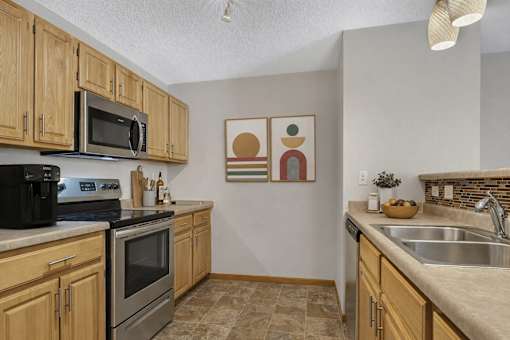 Galley kitchen with wood cabinets and modern appliances at Grand Gateway Apartments, St Cloud, 56301