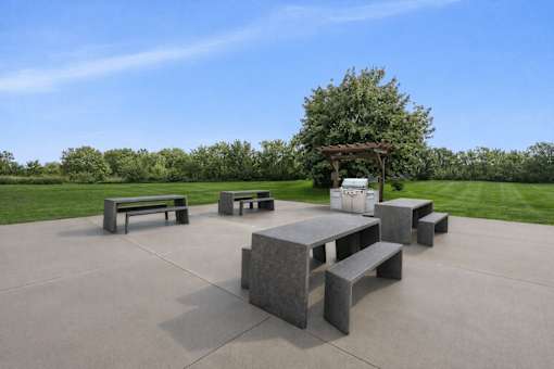 Outdoor picnic area with grilling station and pergola at Prosper West Apartments, Waite Park, MN