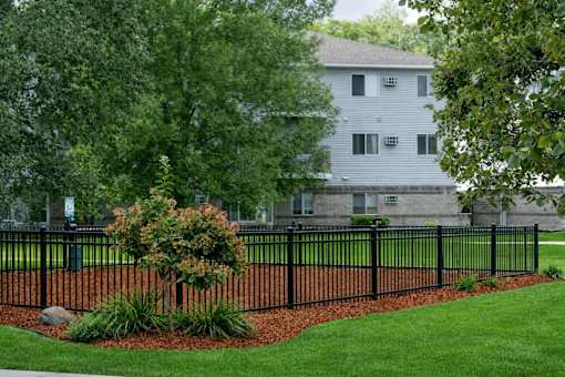 Black fence with landscaping and mulch bed at Regency Park Apartments, St Cloud, 56304