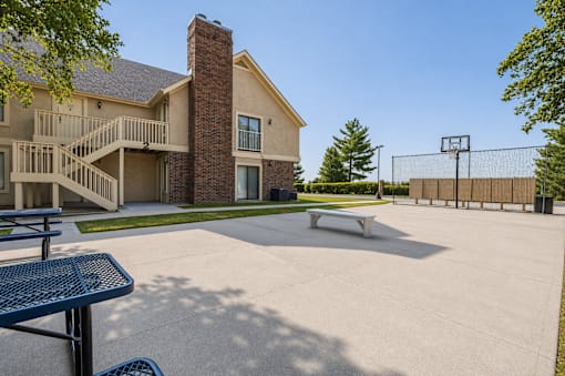 A basketball court is located in front of a large house.