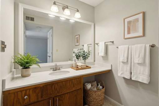 A bathroom with a mirror, sink, and towel rack.