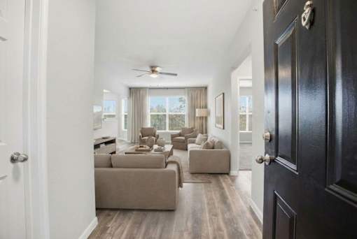 A living room with a brown couch and a ceiling fan.