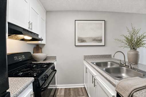 A small kitchen with a black stove and white cabinets.