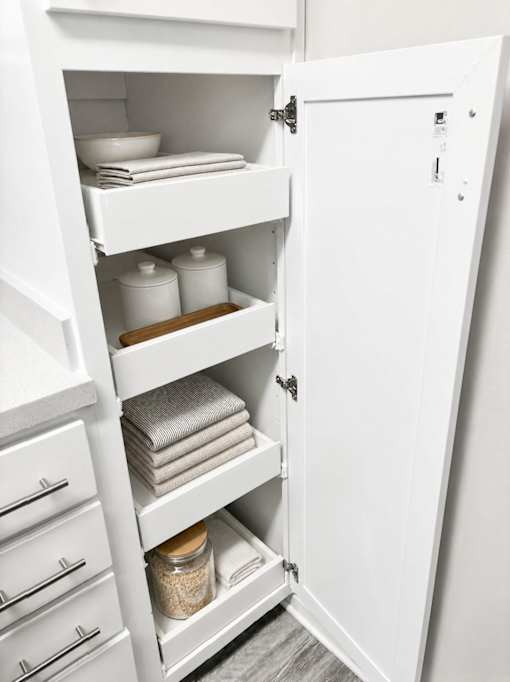 A white kitchen pantry with a door open.