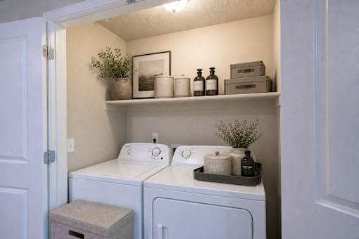 Laundry room with washer and dryer and storage shelf at The Ellison Apartments, Layton, 84041