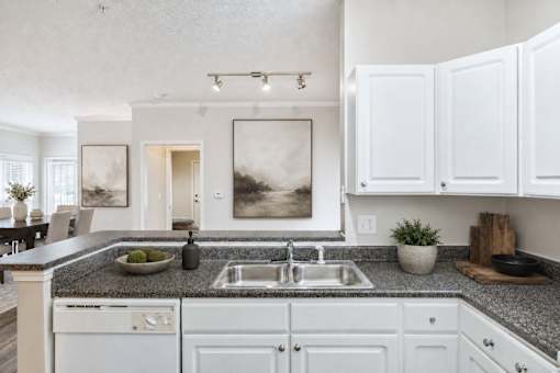 A modern kitchen with white cabinets and a granite countertop.