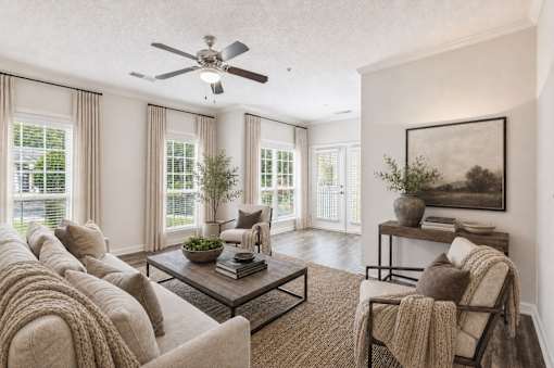 A living room with a couch, a coffee table, and a ceiling fan.