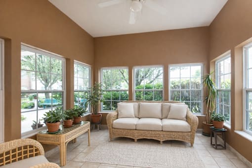 A sunroom with a white couch and a ceiling fan.