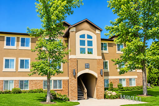 A large building with a brown and tan facade and a large arched entrance. at Slate Canyon Apartments, Apartments, Provo, UT