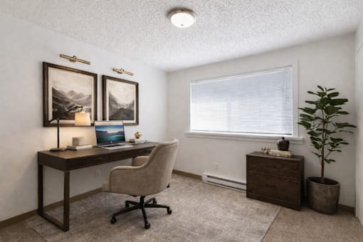 A room with a desk, chair, and two framed pictures on the wall.