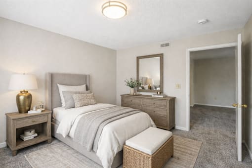 A bedroom with a bed, nightstand, and chair.