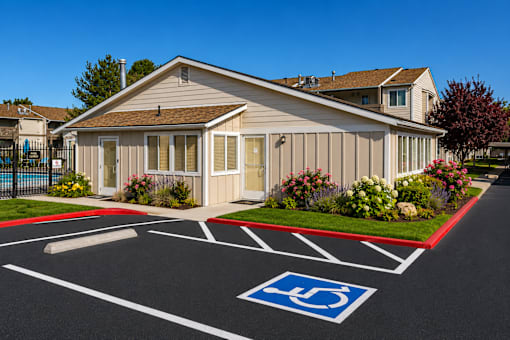 A building with a parking lot in front of it, with a handicap parking space clearly marked.