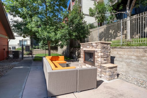 a patio with a fireplace and a couch in front of a fence at Stetson Meadows Apartments, Colorado Springs, CO, 80922