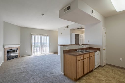 an empty living room with a kitchen and a fireplace at Stetson Meadows Apartments, Colorado Springs, CO