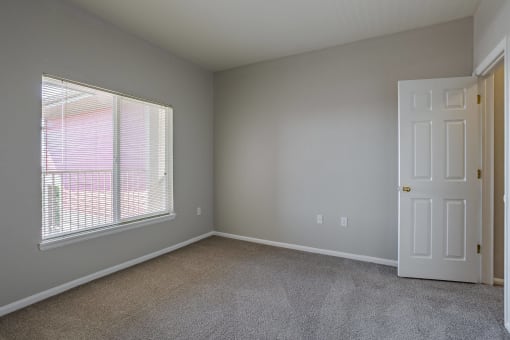 an empty bedroom with a large window and a white door at Stetson Meadows Apartments, Colorado