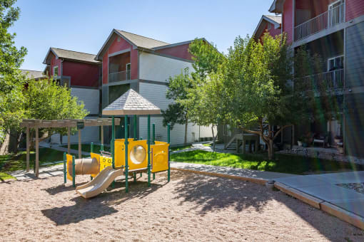 a playground with a yellow play set in front of an apartment building at Stetson Meadows Apartments, Colorado Springs, CO