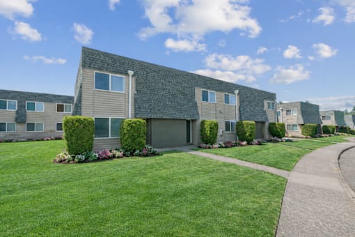 A row of houses with green lawns and hedges in front.