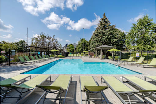 A large swimming pool surrounded by sun loungers and trees.