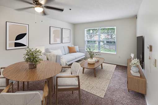 A living room with a couch, chairs, a coffee table, and a ceiling fan.