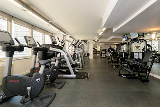 A gym with a variety of equipment including treadmills, stationary bikes, and weight machines.