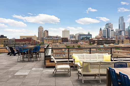A rooftop patio with a table and chairs overlooking a city skyline.