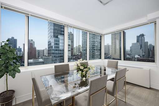 A dining room with a glass table and chairs with a view of the city.