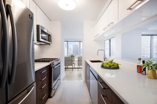A modern kitchen with a refrigerator, microwave, and oven.