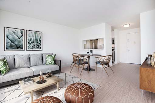 A living room with a grey couch, a coffee table, and a dining table with chairs.