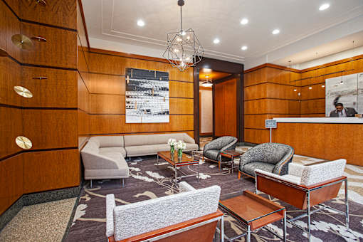 A modern waiting room with a wooden panelled wall and a variety of seating options.