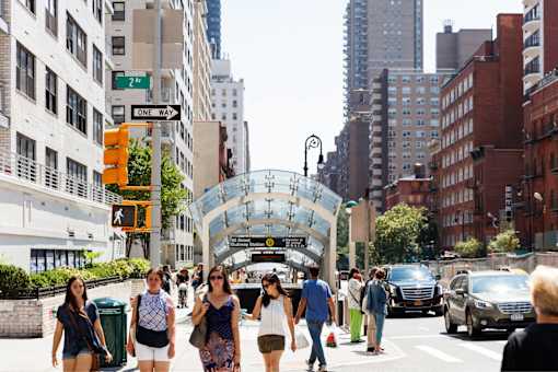A group of people are walking down a street with a one way sign.