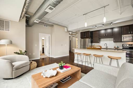 A modern living room with a kitchen in the background.