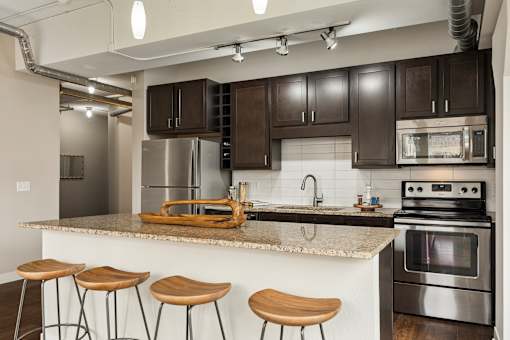 A kitchen with a stove, oven, and bar stools.