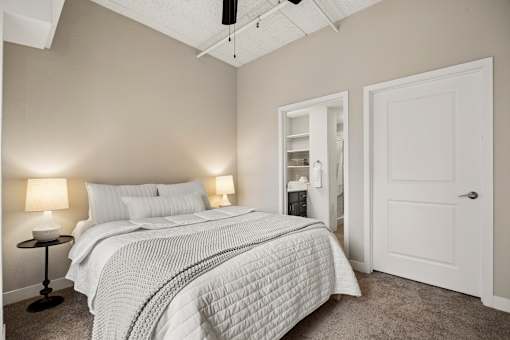 A bedroom with a bed, two lamps, and a ceiling fan.