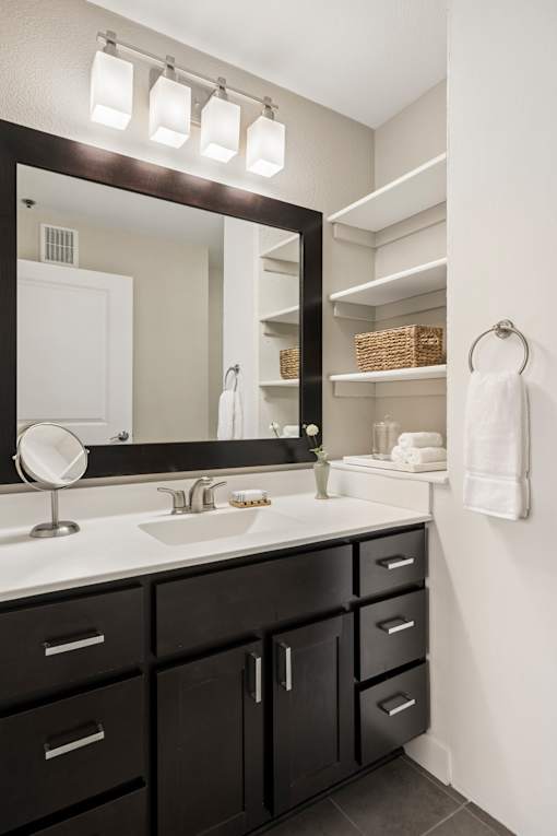 A bathroom with a sink, mirror, and lights.