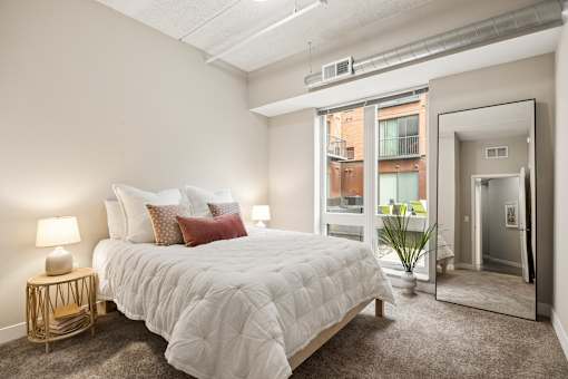 A bedroom with a large bed and a view of a balcony outside.