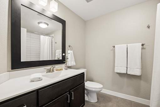 A bathroom with a white counter top and a white toilet.