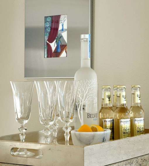 A bottle of Belvedere vodka is on a counter with glasses and bottles of Fever tree tonic water.
