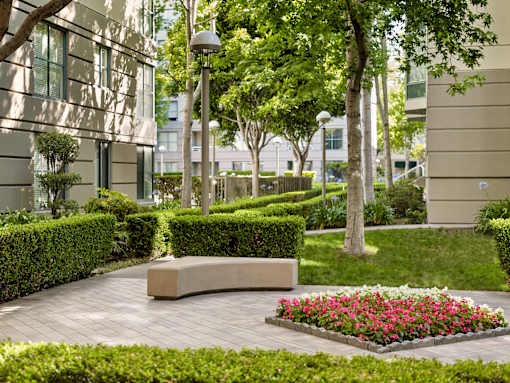 A well-manicured garden with a bench and a flower bed in the foreground.