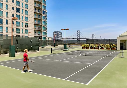 A tennis court with a person playing tennis.