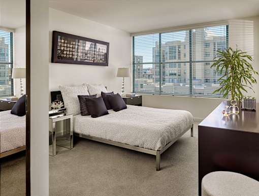 A bedroom with a large bed and a plant on the desk.