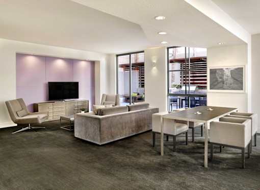 A modern living room with a grey carpet and a purple wall.